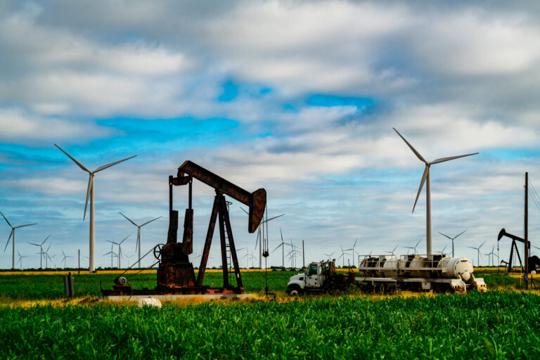 22 03 21 an oil well with clean energy wind turbines in the background gettyimages 1263933136