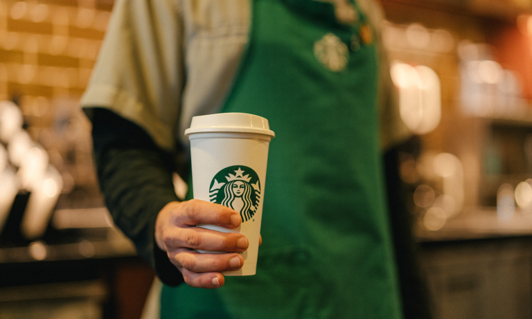 starbucks employee holds a coffee cup with company logo is sbux