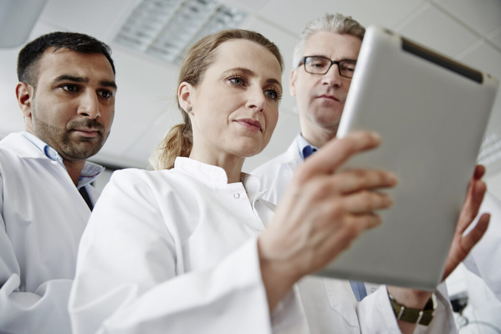 three scientists look at tablet while worried