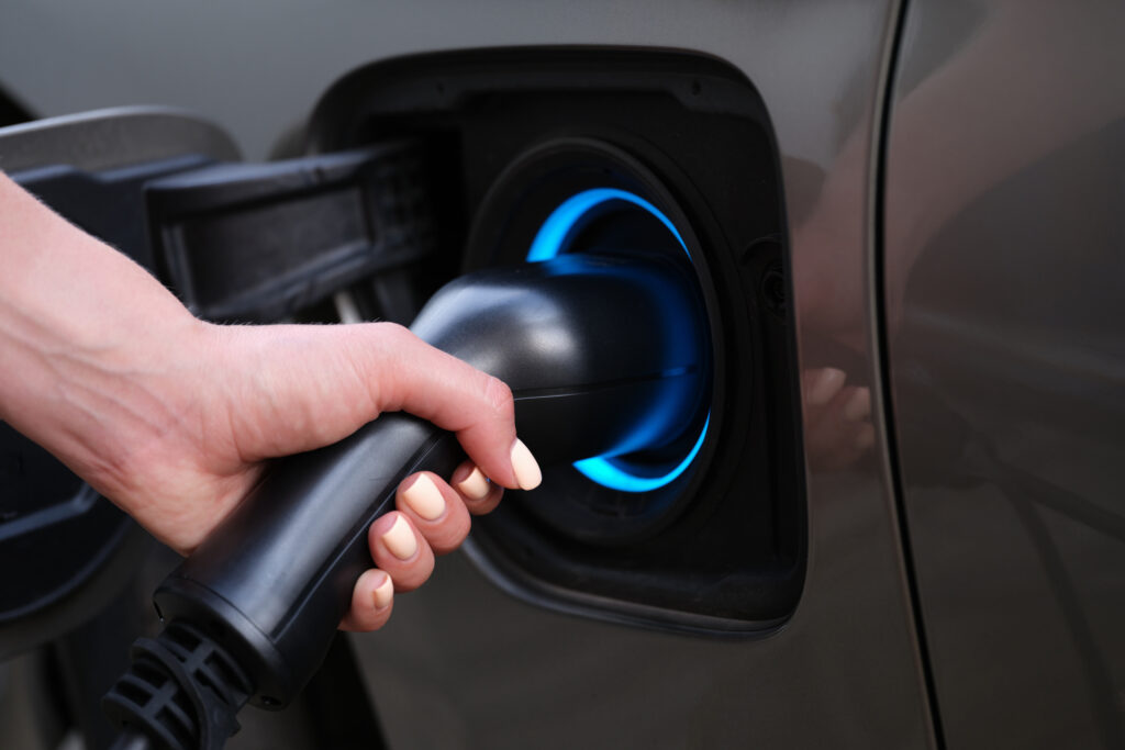 hand holding a charger plugged into an electric vehicle