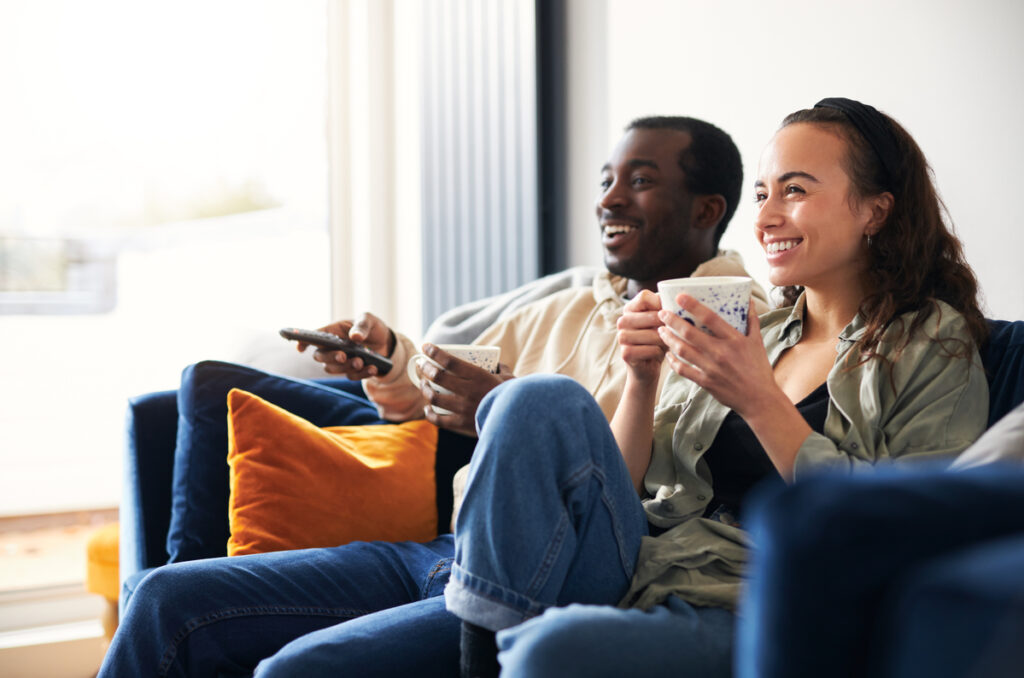 two people sitting on a couch watching streaming