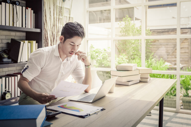 investor considers papers while sitting near books