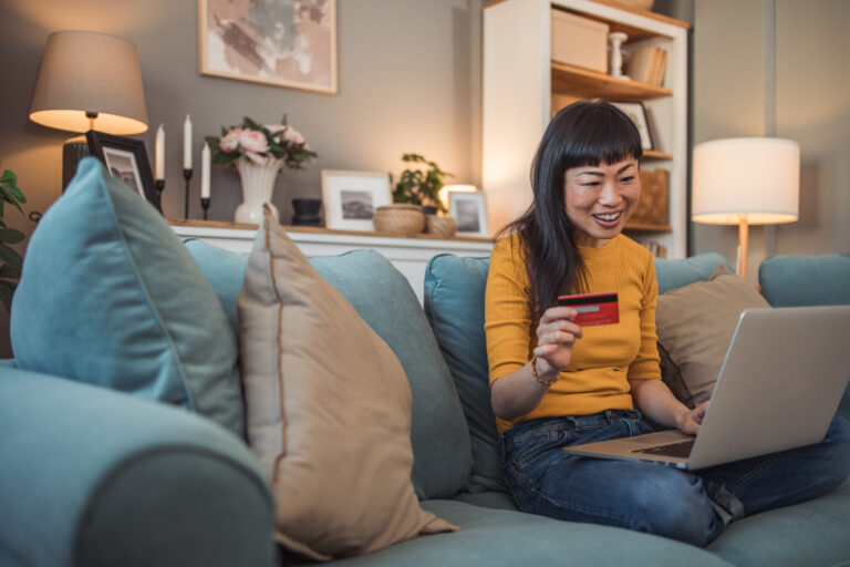 person holding payment card while using a laptop pc