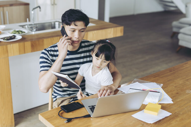 person talking on phone and looking at laptop with child on lap